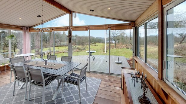 A covered patio with a dining table, chairs, and a view of the outdoors.