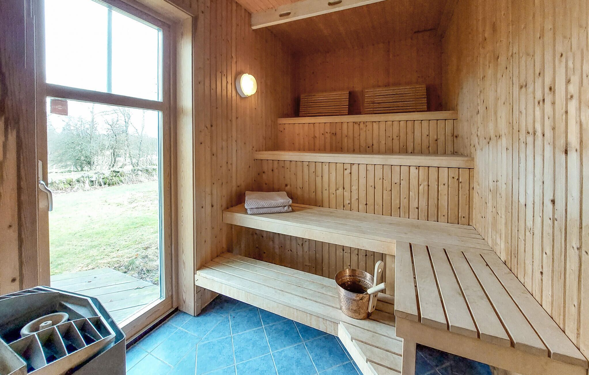 Un cuarto de sauna con paredes de madera, un banco, un estante y un balde.