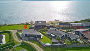 A coastal residential area with modern houses, a grassy lawn, and a body of water. - Awesome home in Juelsminde with WiFi (Juelsminde)