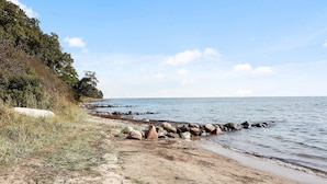 A sandy beach with a rocky breakwater and dense foliage on the left. - Awesome home in Juelsminde with WiFi (Juelsminde)