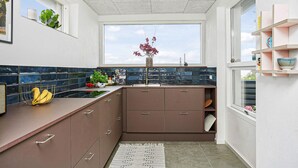 A modern kitchen with a window, dark blue tiles, and a plant on the counter. - Awesome home in Juelsminde with WiFi (Juelsminde)
