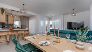 Moderni keittiö, jossa on ruokailutila, televisio ja sohva.