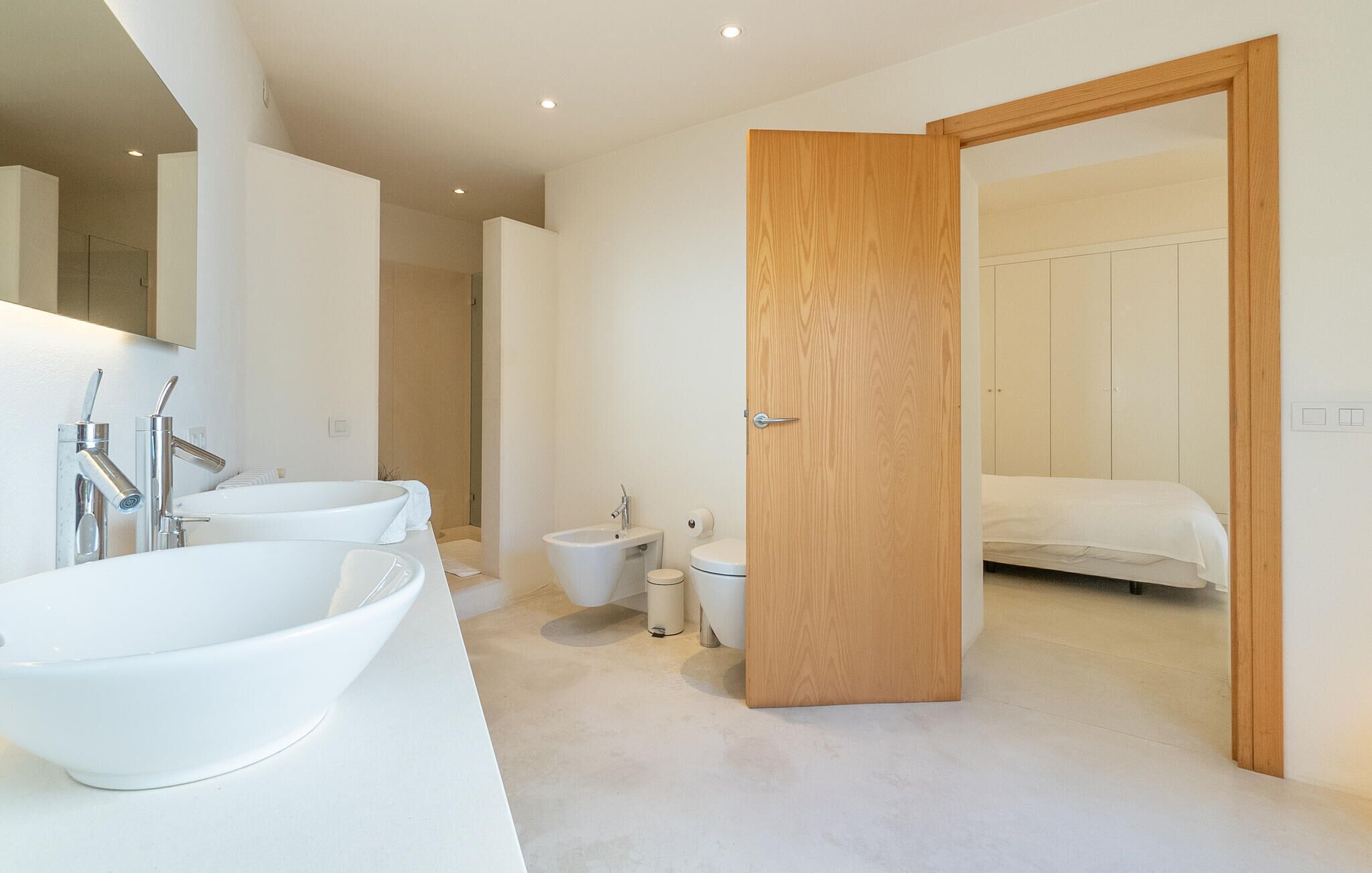 Un baño moderno con un lavabo grande blanco, dos llaves, inodoro y zona de ducha.
