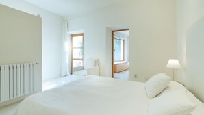 A modern bedroom with a large bed, a radiator, and two windows.