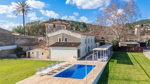 A villa with a swimming pool, a covered patio, and a view of the surrounding countryside.