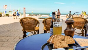 Uma mesa com uma garrafa de cerveja Blanche de Namur, um copo e fatias de pão.