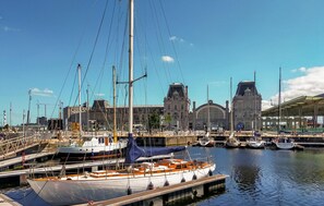 A marina with boats docked, a large building with a clock tower, and a covered area with seating. - Amazing apartment in Oostende with WiFi (Oostende)