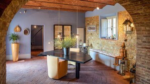 Uma área de refeições com uma mesa comprida, cadeiras e um vaso de planta.