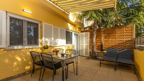 A patio with a table and chairs, a wooden fence, and a tree. - Cozy apartment in Dramalj with house sea view (Dramalj)