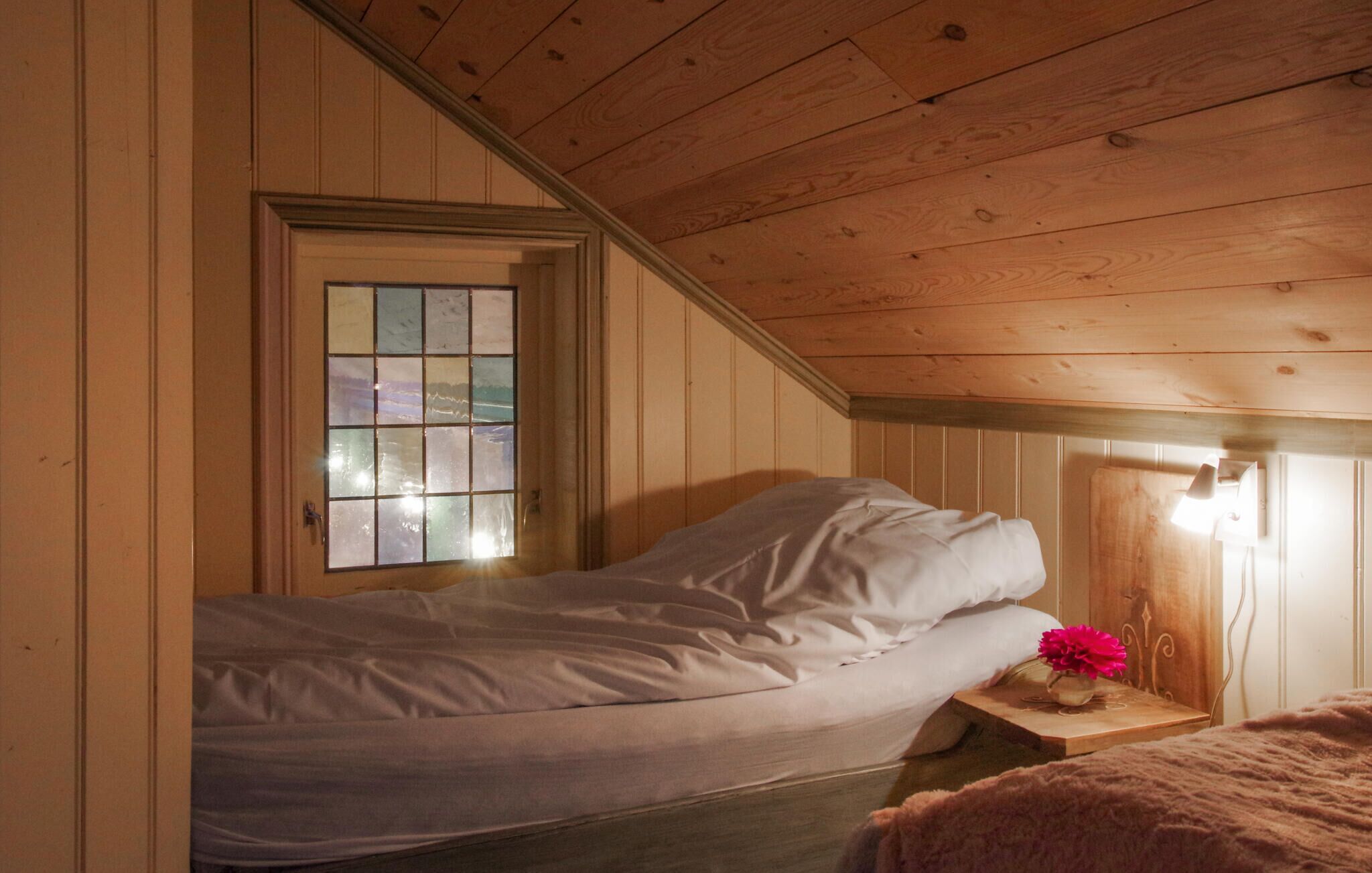A single bed in a room with wooden walls and a sloped ceiling.