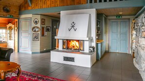 Un hall d’entrée chaleureux avec une cheminée centrale, des murs en bois et un mur d’accent en pierre.