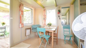 A dining area with a table, chairs, and a fan. - 2 bedroom nice (sta)caravan in CASALABRIVA (CASALABRIVA)