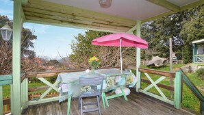 A covered outdoor seating area with a table and chairs, a pink umbrella, and a wooden deck. - 2 bedroom nice (sta)caravan in CASALABRIVA (CASALABRIVA)