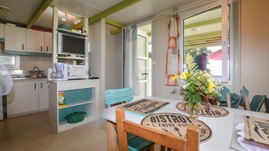 A cozy kitchen with a dining table set for two, a vintage sign reading "BISTROT L'ENTRE-POTS", and a window with a view of the outside. - 2 bedroom nice (sta)caravan in CASALABRIVA (CASALABRIVA)