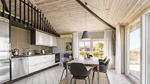 Eine moderne Küche mit weißen Schränken, Edelstahlgeräten und einem großen Fenster mit Blick auf einen Garten.