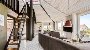 Ein geräumiger Wohnbereich mit moderner Treppe, einem Essbereich und großen Fenstern mit Blick ins Freie.