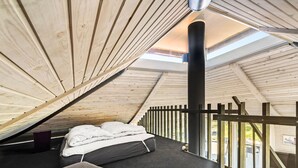 Ein gemütliches Schlafzimmer im Dachgeschoss mit einem Bett, einer Holzbalkendecke und einem Dachfenster.