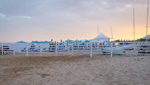 Una playa con valla blanca, barcos y una carpa.