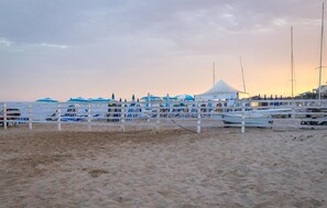 Una spiaggia con una recinzione bianca, barche e una tenda.