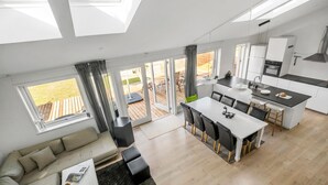 Et moderne køkken med spiseplads, store vinduer og et hyggeligt siddeområde.