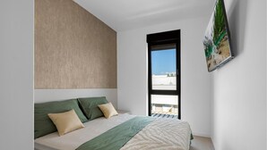 A bedroom with a bed, a window, and a painting on the wall.
