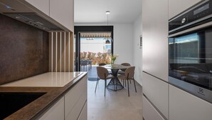 A modern kitchen with a built-in oven, a dining area with a table and chairs, and a view of the outdoors.