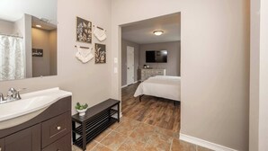 Une chambre à coucher avec un lit, une télévision et une salle de bain équipée d’un lavabo et d’un miroir.