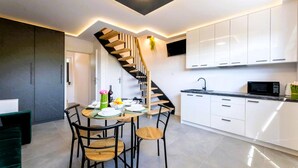 A modern kitchen with white cabinets, a black countertop, and a wooden staircase. - 3 bedroom amazing home in Wodnica (Wodnica)