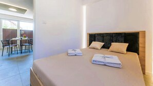 A modern hotel room with a large bed, a dining area with chairs, and a view through the window. - 3 bedroom amazing home in Wodnica (Wodnica)