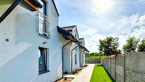 A row of white houses with a narrow pathway and a green lawn. - 3 bedroom amazing home in Wodnica (Wodnica)