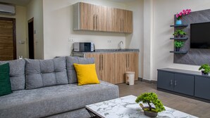 A modern living room with a grey sofa, a small coffee table, and a TV mounted on the wall. - Venue 360 (Freetown)
