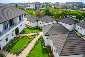 A modern building with multiple units, a central courtyard with a lawn and flower beds, and a view of surrounding residential area. - Venue 360 (Freetown)