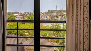 A view from a balcony with a metal railing, overlooking a residential area with houses and greenery. - Venue 360 (Freetown)