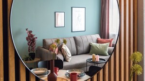 A modern living room with a sofa, cushions, a coffee table, and a mirror reflecting the room. - Szafir - by Kairos Apartments (Gliwice)