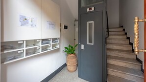 Ein Flur mit einer Holztreppe, einer grauen Tür und einem Blumentopf.