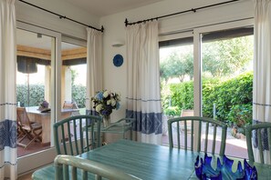 Un comedor con una mesa y sillas, un florero con flores y vistas al verde exterior.