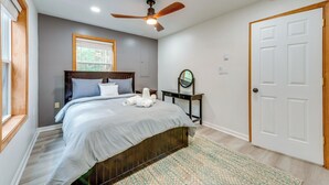 A bedroom with a bed, a ceiling fan, a window, and a door. - Lakefront Poconos Cabin w/ Deck & Game Room (Blakeslee)