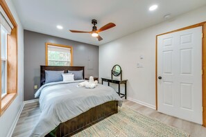 Un dormitorio con una cama, ventilador de techo, ventana y puerta.