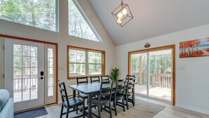 A spacious dining area with a large table and chairs, large windows, and a view of the outdoors. - Lakefront Poconos Cabin w/ Deck & Game Room (Blakeslee)