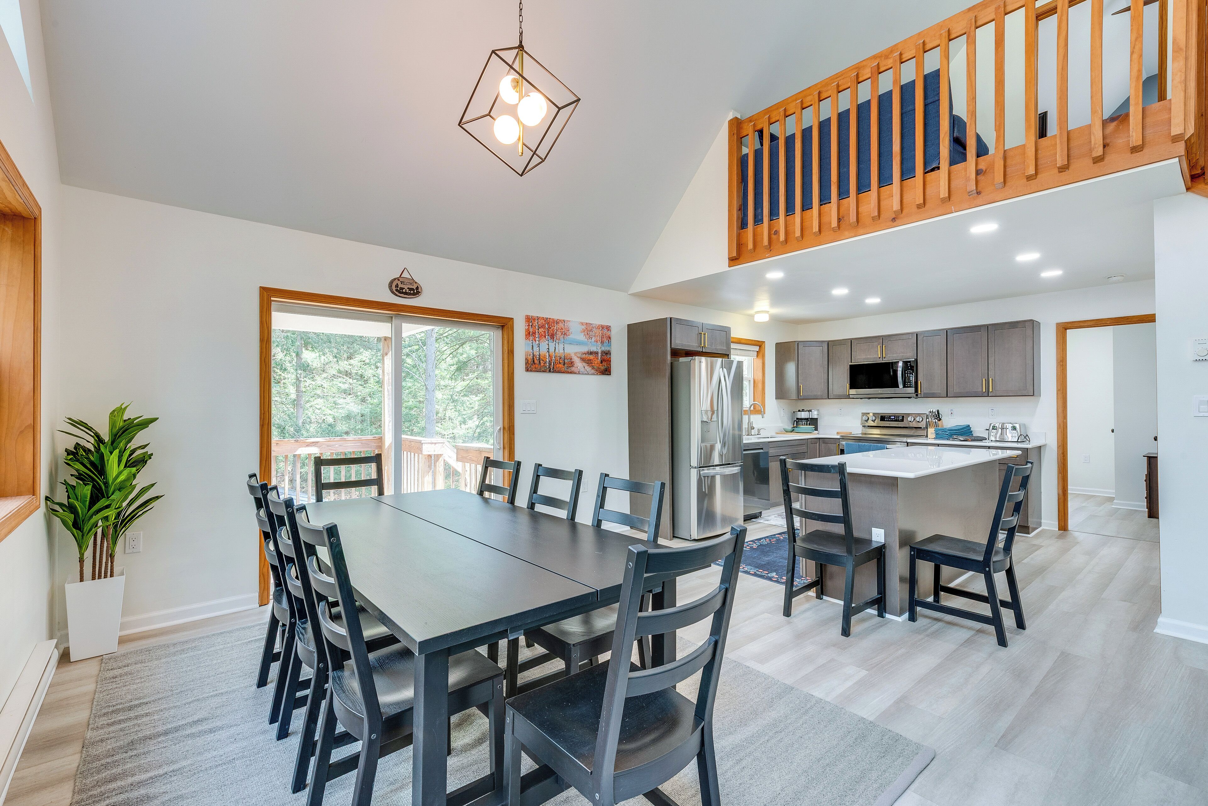 A spacious dining area with a large table and chairs, a kitchen with modern appliances, and a wooden staircase.