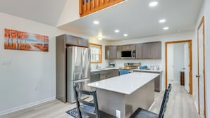 A modern kitchen with a central island, stainless steel appliances, and wooden cabinetry. - Lakefront Poconos Cabin w/ Deck & Game Room (Blakeslee)