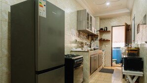 A compact kitchen with a refrigerator, stove, microwave, and cabinets.