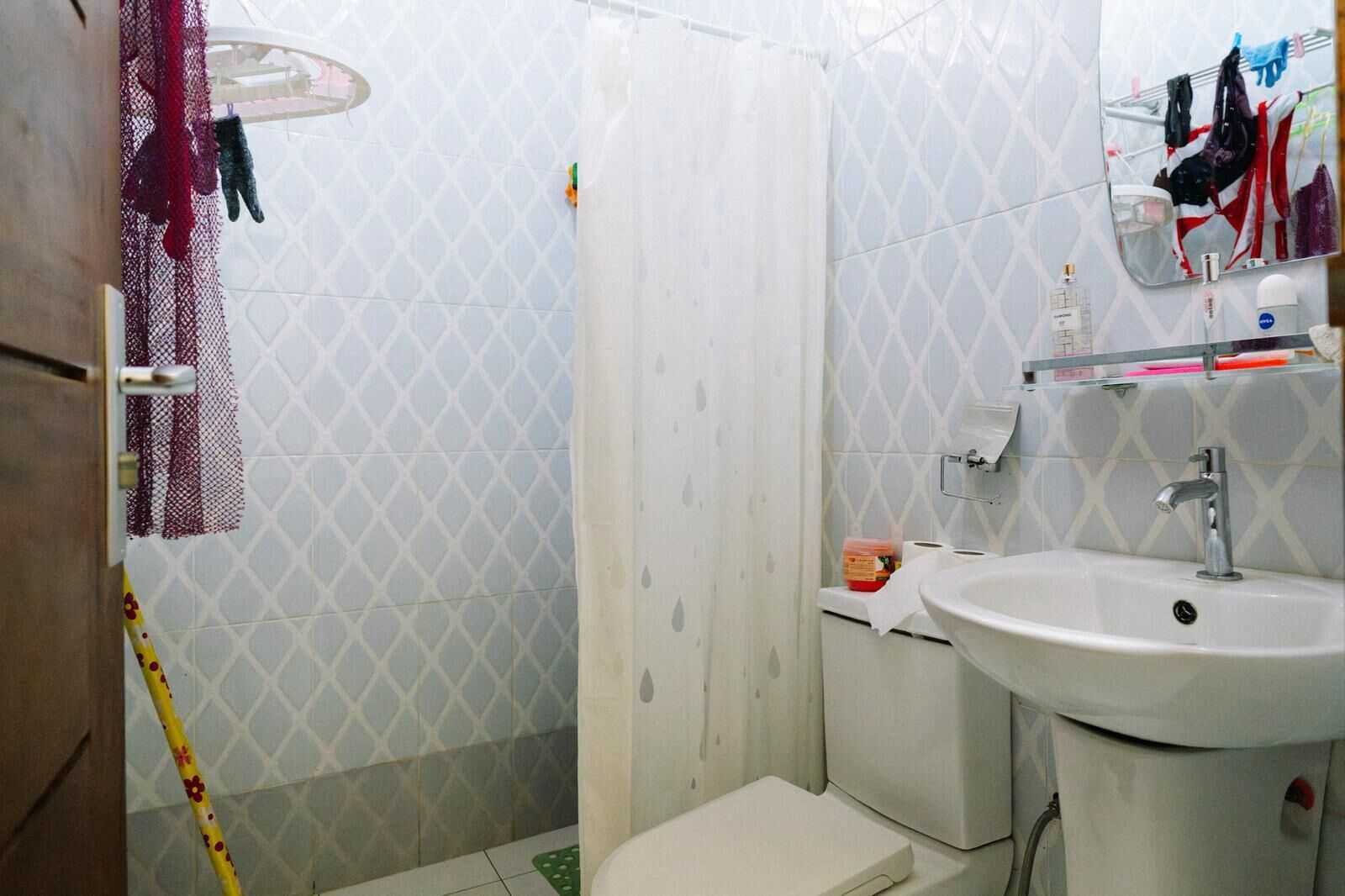 Un baño con ducha, inodoro, lavamanos y espejo con artículos de aseo.