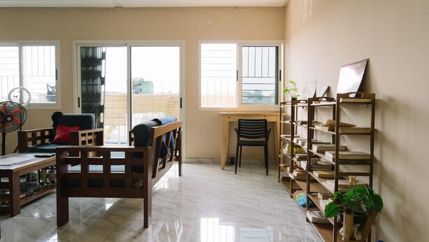 A spacious living room with a wooden sofa, a desk, and a bookshelf.