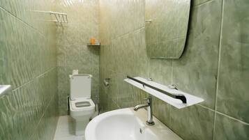 Baño con inodoro, lavabo y repisa con artículos de aseo.