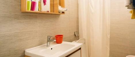 Une salle de bain avec un lavabo, un miroir et des toilettes.