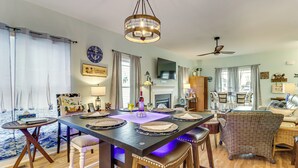 Een eetruimte met een tafel voor vier personen, een kroonluchter en een televisie boven de open haard.