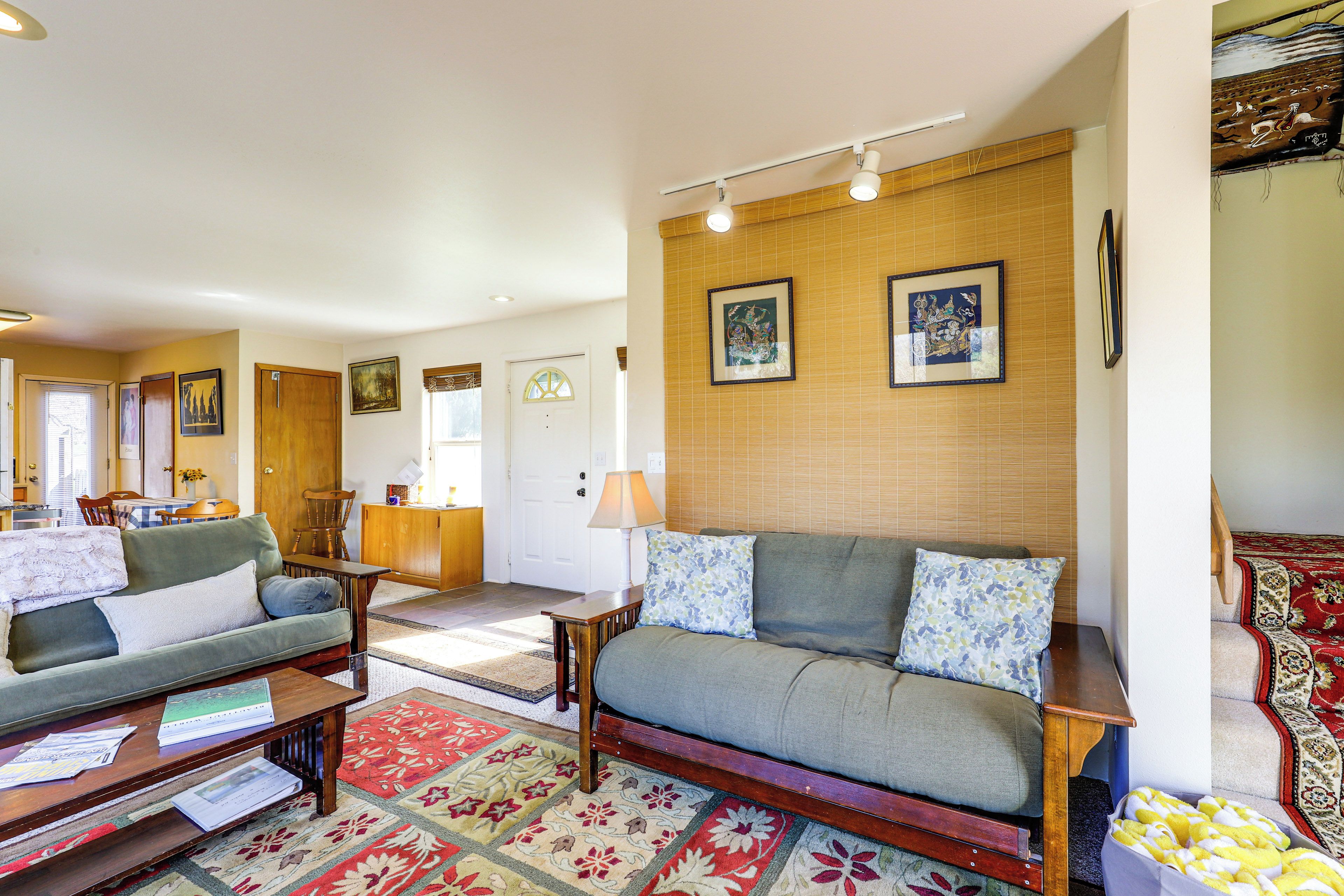 A living room with a sofa, a coffee table, and a rug. There is a door leading to another room.