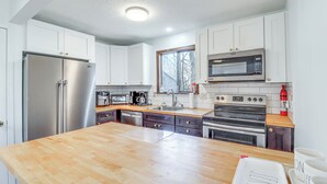 A modern kitchen with white cabinets, stainless steel appliances, and a wooden countertop. - 3 Mi to Tobyhanna State Park: Home w/ Serene Deck! (Tobyhanna)