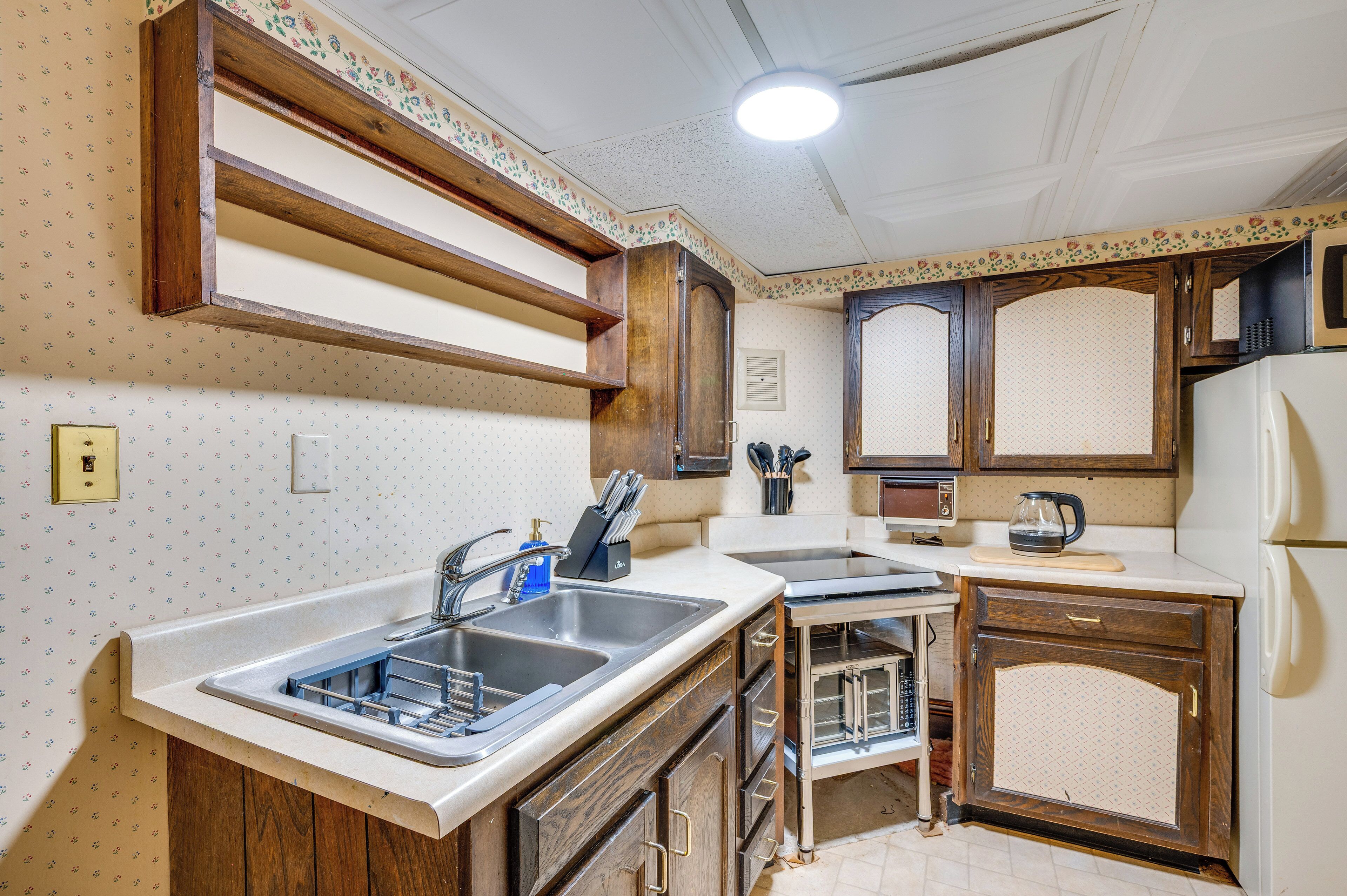 A kitchen with wooden cabinets, a sink, and a refrigerator.